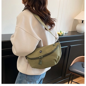 Olive green crescent crossbody bag with OK logo shown worn from side rear view