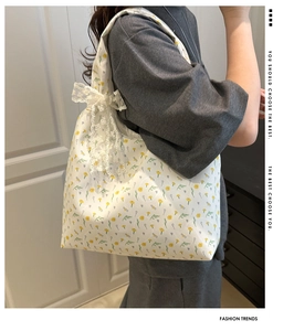 Floral canvas tote bag with white lace bow detail shown on shoulder for summer fashion
