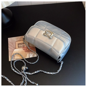 Détail du sac matelassé métallisé avec boucle irrégulière et bandoulière en chaîne chic