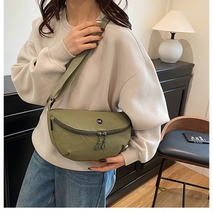 Detail of army green nylon crossbody bag showing the adjustable strap and circular logo