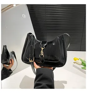 Dettaglio della borsa hobo in pelle verniciata nera con chiusura a pistone dorata