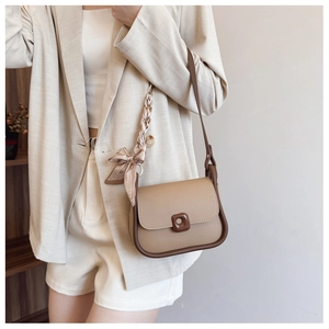Detail of khaki crossbody bag with brown piping and striped silk scarf on the strap