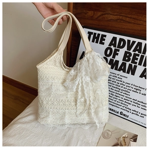 Close-up of cream lace tote bag with floral embroidery and large decorative bow detail