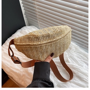 Close-up of the woven straw texture and adjustable brown canvas strap of the waist bag