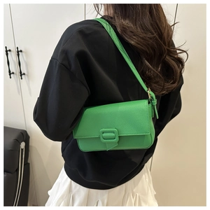 Close-up of bright green baguette bag with lychee texture and buckle on shoulder