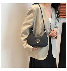 Detail of black leather hobo bag with gold D-buckle worn on model shoulder