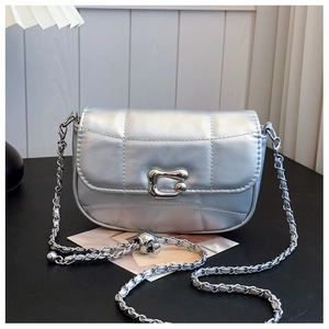Détail d'un sac argenté matelassé avec boucle métallique irrégulière et bandoulière chaîne