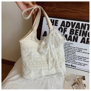 Detailed close-up of layered off-white lace tote bag with a decorative side ribbon bow