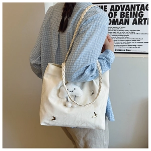 White tote bag with silver butterfly patch and cloud pendant worn by a model