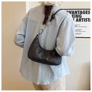 Detail of black crescent shoulder bag featuring knotted strap and silver ring connector