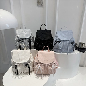 Cinq sacs à dos en nylon à nœuds avec broderie Nika sur un présentoir blanc moderne