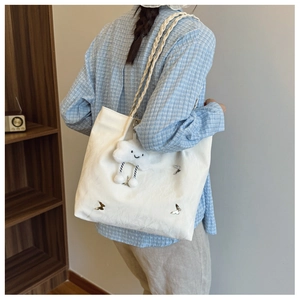 Detail of white tote bag with silver butterfly charms and plush cloud keychain accessory
