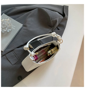 Detailansicht der weißen Schultertasche mit schwarzer Klappe und Innenraum für Kosmetik