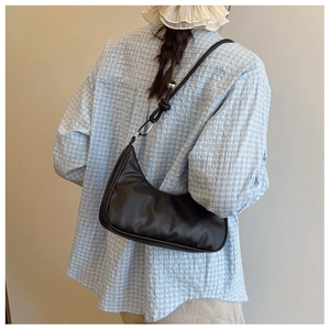 Detail of a black crescent hobo bag with knotted shoulder strap and metal ring hardware