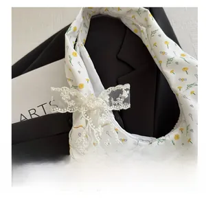 Detail view of floral canvas bag featuring a large white lace bow and bee patterns