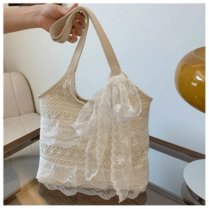 Close-up of cream lace tote bag featuring detailed hollow floral patterns and side bow