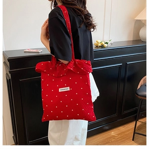 Détail du sac cabas rouge à fleurs avec bords volantés et écusson Fashion Bag porté