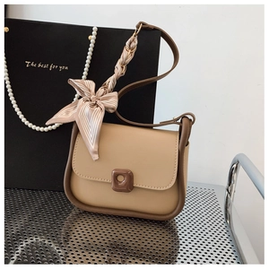 Detail view of khaki leather crossbody bag with brown trim and decorative silk scarf