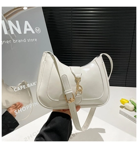 Dettaglio di una borsa a mezzaluna in vernice bianca con chiusura a moschettone dorata