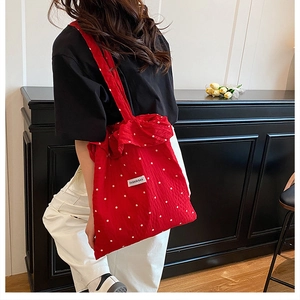 Détail du cabas en toile rouge à fleurs avec étiquette Fashion Bag sur modèle