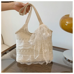 Detailed macro view of layered lace ruffles and a large bow on this beige tote bag
