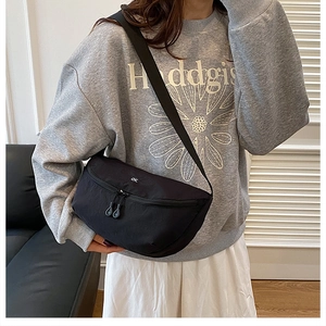 Detail of black half-moon crossbody bag with minimalist white OK print and wide strap