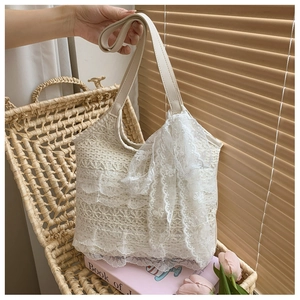 Detail of white lace tote bag with layered floral ruffles and a large decorative bow