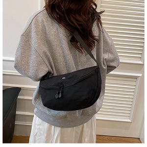 Detail of black nylon crescent bag with small ok embroidery and double zipper closure