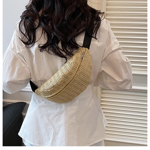 Detailed view of natural straw woven texture and black strap on a trendy crossbody chest bag
