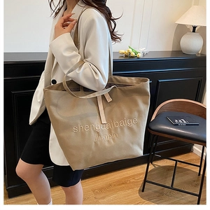 Gros plan détaillé d'un sac cabas en toile kaki avec broderie de qualité sur la large bandoulière