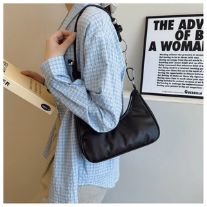 Detail of black crescent shoulder bag featuring silver metal rings and carabiner hardware