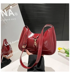 Dettaglio della borsa a spalla in pelle rossa lucida con fibbia dorata decorativa