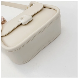 Detail view of off-white structured leather handbag with decorative silk scarf and neat seams