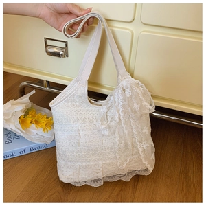 Detail of delicate cream lace mesh fabric and large lace bow on a summer tote bag