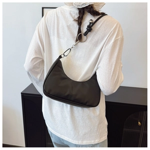 Detail of black crescent shoulder bag with silver ring hardware and knot strap