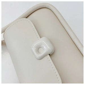 Close-up of cream leather shoulder bag with square snap buckle and fine stitching