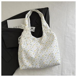 Detail of floral canvas tote bag featuring delicate white lace bow and yellow flower pattern