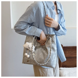 Detail of silver metallic tote bag featuring butterfly accent and plush cloud charm
