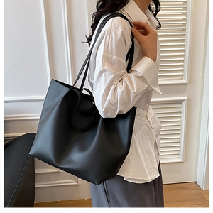 Minimalist black tote bag in pebbled leather shown on model for shoulder style