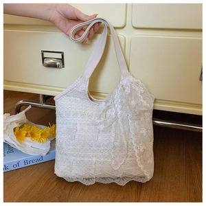 Detailed macro of white lace tote bag with crochet floral patterns and leather handle