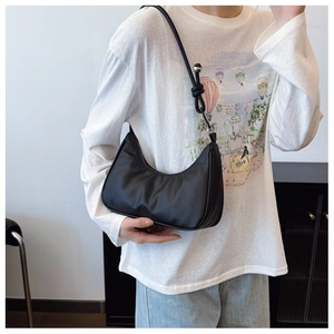 Detail of black crescent hobo bag featuring knotted strap and silver metal sphere accent