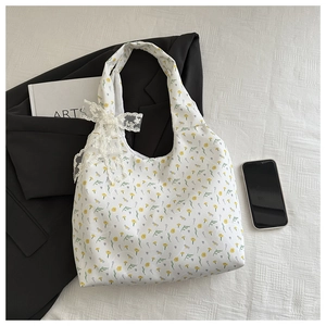 Close-up of floral canvas tote bag with white lace bow and elegant yellow flower print