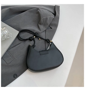 Detail der schwarzen halbmondförmigen Schultertasche mit Knotengurt auf Anzug