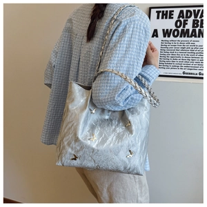 Silver metallic tote bag with butterfly charms and woven strap on model shoulder