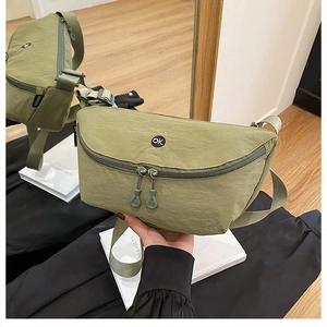 Detail of army green nylon crossbody bag with circular OK patch and adjustable strap