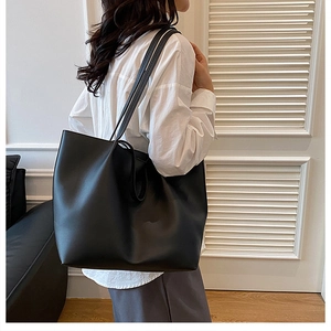 Side view of a large black leather tote bag worn by a model for daily work commute