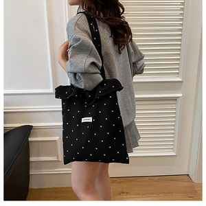 Vue détaillée du sac cabas en toile noire à motifs floraux et étiquette mode