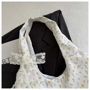 Detail of floral canvas tote bag with bee print and lace bow accessory on a blazer background