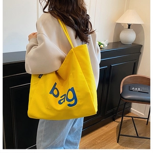 Detail of a bright yellow canvas tote bag with blue bag print and functional front pocket