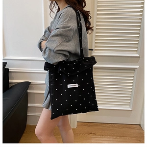 Détail du cabas en toile noire à fleurs avec étiquette Fashion Bag et fines bandoulières